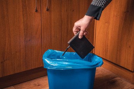 A man throws a WiFi router in the trash. Man's hand with a WiFi router and a trash can in blueの写真素材