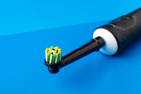 Electric toothbrush. A black toothbrush on a blue background, close upの写真素材