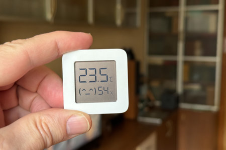 Comfortable humidity and temperature in the apartment. Close-up of a man's hand holding a hygrometer and thermometer.の写真素材