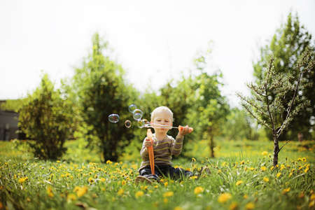Baby sitting in the garden playing water balloonsの写真素材