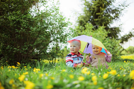two babies sitting in the garden with rainbow umbrella
の写真素材