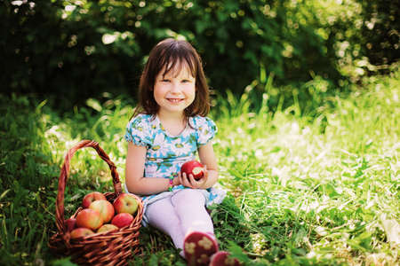 Young girl holding apples in the basket.の写真素材