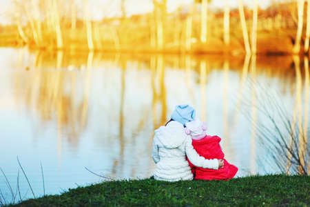 The children happy outdoors sitting on river.の写真素材