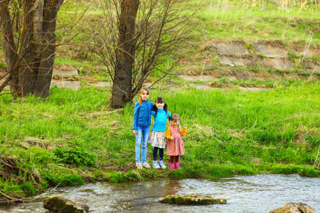 The children happy outdoors sitting on river.の写真素材