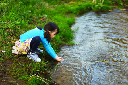 The children happy outdoors sitting on river.の写真素材