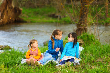 The children happy outdoors sitting on river.の写真素材