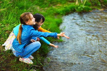 The children happy outdoors sitting on river.の写真素材