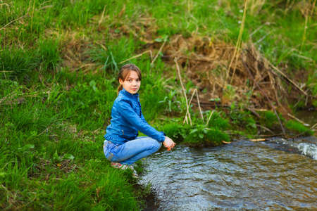 The children happy outdoors sitting on river.の写真素材