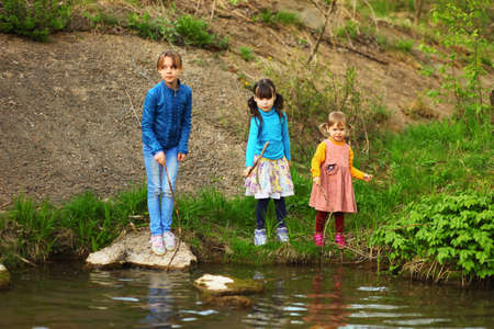 The children happy outdoors sitting on river.の写真素材