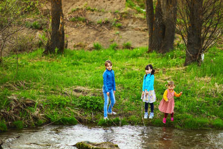 The children happy outdoors sitting on river.の写真素材