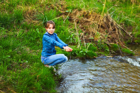 The children happy outdoors sitting on river.の写真素材
