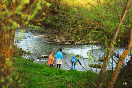 The children happy outdoors sitting on river.の写真素材