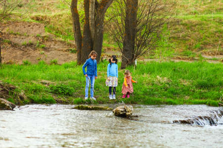 The children happy outdoors sitting on river.の写真素材