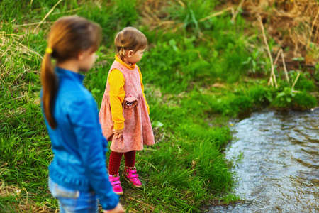 The children happy outdoors sitting on river.の写真素材