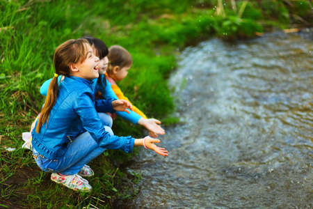 The children happy outdoors sitting on river.の写真素材