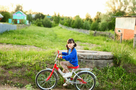Little girl riding her bike through the village.の写真素材