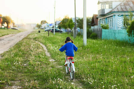 Little girl riding her bike through the village.の写真素材
