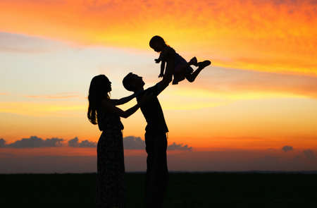 Silhouettes of people on bright evening sunset.の写真素材