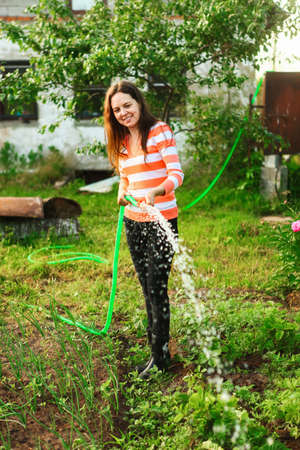 Young girl watering the beds in garden.の写真素材