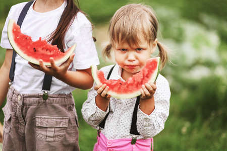 The Little girl eating watermelon a outdoors.の写真素材