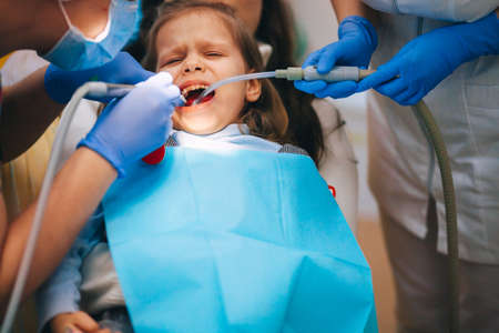 A little girl is curing a tooth from a dentist.の写真素材