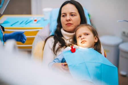 A little girl is curing a tooth from a dentist.の写真素材