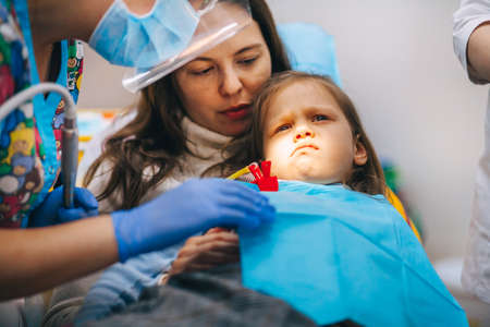A little girl is curing a tooth from a dentist.