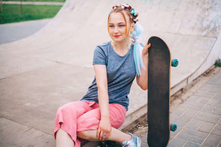 The Young woman portrait with a skateboard.