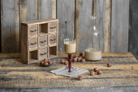 Cream liqueur in glass and bottle with hazelnut on wooden backgrの写真素材