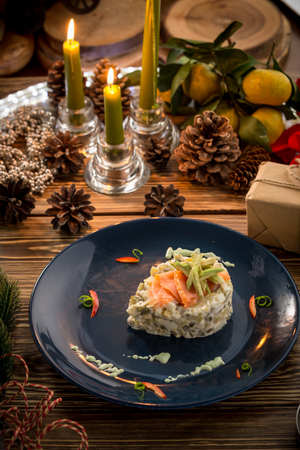Russian traditional salad Olivier with slices of salmon on top with new year decoration on wooden table. Studio shotの写真素材