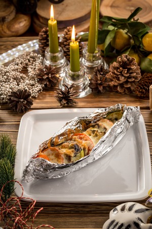 French traditional dish ratatouille with eggplant, zucchini, tomatoes, sweet pepper, onion, garlic on white plate on christmas decorated background. Studio shotの写真素材