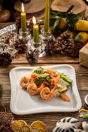 Seafood Green Salad with Salmon, Avocado and Shrimps on white plate on christmas decorated background. Studio shotの写真素材