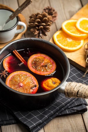Composition with spicy mulled wine, oranges and pine cones on wooden backgroundの写真素材