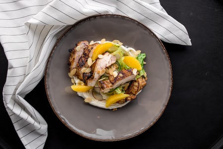Salad with roasted duck breast and orange with white napkin on black backgroundの写真素材