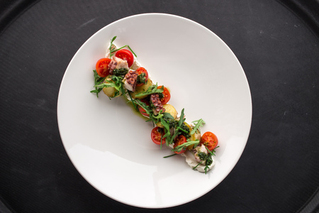octopus salad with potatoes and cherry tomatoes on black backgroundの写真素材