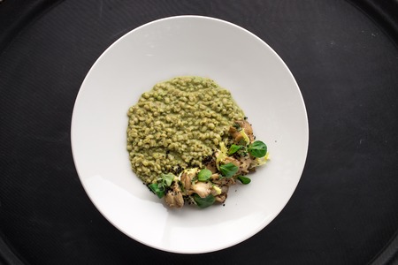Dish with delicious risotto and forest mushrooms on black background. Studio shotの写真素材