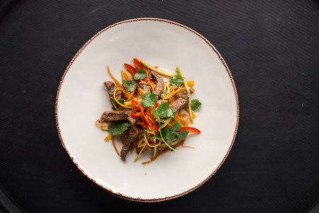 Asian Sliced Beef Salad with pepper and Carrots on black background. Studio shotの写真素材