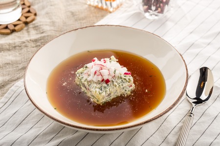 Summer cold soup okroshka with radish, cucumber and dill served on table studio shot