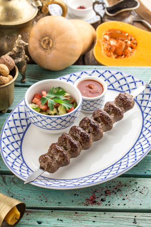kofta kebab on skewer with fresh vegetables and ketchup on blue wooden table side viewの写真素材