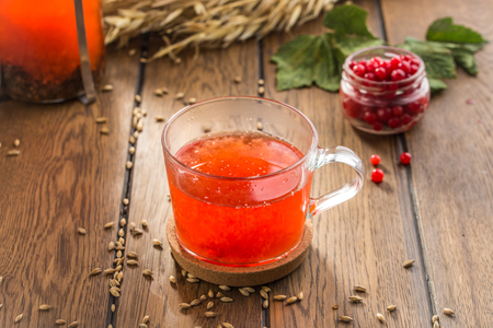 Cup of tea with red berries and wheat spikes on wooden table side viewの写真素材