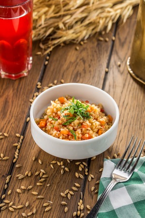 Bulgur with tomatoes and squash and glass of berry drink on wooden table side viewの写真素材
