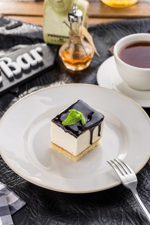 Vanilla souffle with dark chocolate glaze and cup of tea on black table side viewの写真素材