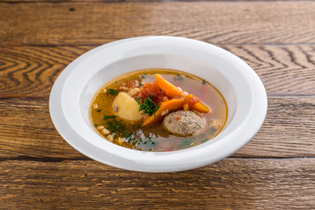 Soup with meat balls and vegetables isolated on wooden background side viewの写真素材