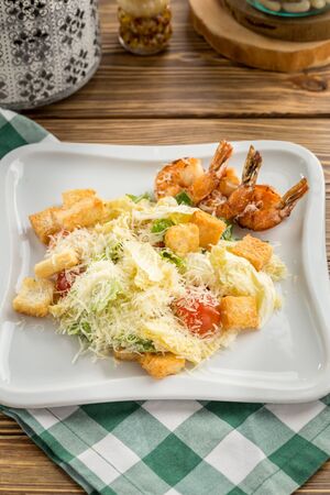 Healthy Grilled Caesar Salad with shrimp, parmesan Cheese and Croutons on wooden table side viewの写真素材