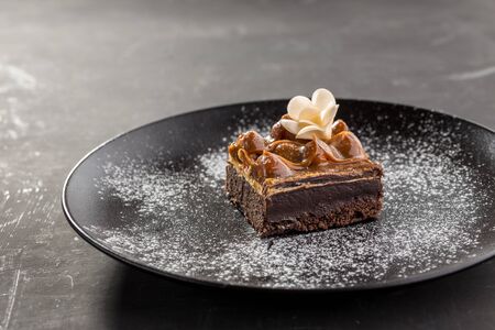 Brownies with Caramel Sauce on black plate on black background side viewの写真素材