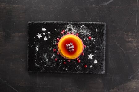 berry orange pudding on stone plate with cranberry on black background top viewの写真素材
