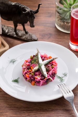 Salted sardines and beetroot salad with berry drink on wooden table side viewの写真素材