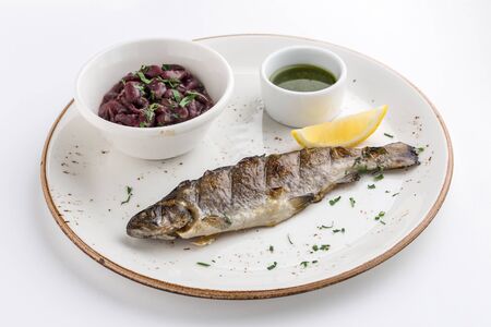Grilled whole fish with red bean, lemon and soy sauce isolated on white background side view
