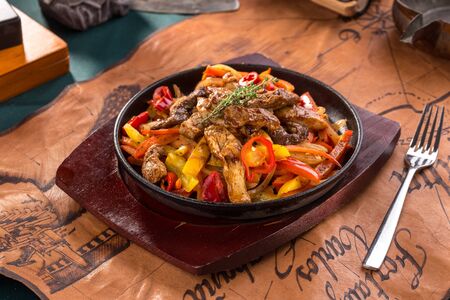 Beef fajitas with colorful vegetables in pan on old map background side viewの写真素材