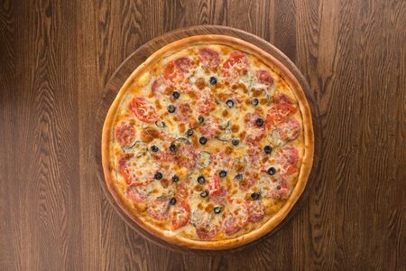 Pizza pepperoni with olives isolated on wooden background top viewの写真素材